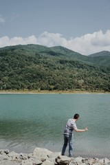 Fototapeta na wymiar Man throwing stone in lake