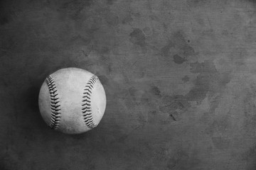Old baseball ball on texture background in black and white, copy space for sports graphic concept.