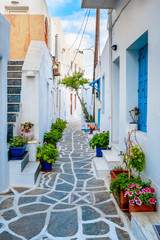 Obraz na płótnie Canvas Picturesque narrow street with traditional whitewashed houses with blooming flowers of Naousa town in famous tourist attraction Paros island, Greece