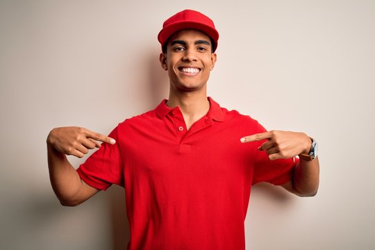 Young handsome african american man wearing casual polo and cap over red background looking confident with smile on face, pointing oneself with fingers proud and happy.