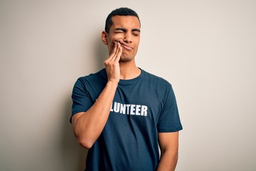 Young handsome african american man volunteering wearing t-shirt with volunteer message touching...