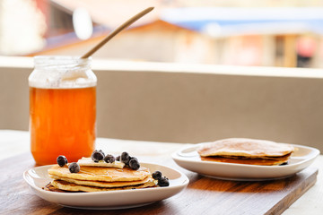 low angle view on white plate on the wooden board table with pancakes and butter blueberries over...