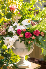 Bouquet of pink and white flowers in a plinth. Green leaves on the background.