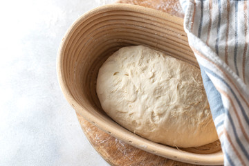 Homemade bread. Ball of raw dough on wooden board on white background.