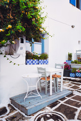 Picturesque narrow street with traditional whitewashed houses with cafe tables of Naousa town in famous tourist attraction Paros island, Greece