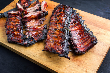Gegrillte Schweine Spare Loin Ribs St Louis Schnitt mit Honig Chili Marinade aufgeschnitten und verbrannt  als closeup auf einem Holz Schneidebrett