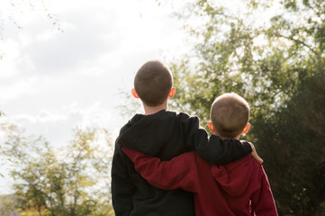 Niños de espalda abrazados mayor y menor en la naturaleza