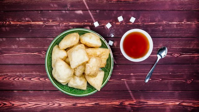 Baursak with a cup of tea - traditional Kazakh Asia food national bread Rotates in plate on a beautiful wooden background. Top view