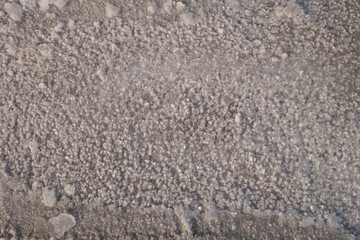 Sandy bottom of a dried reservoir with cracks and salt crystals.