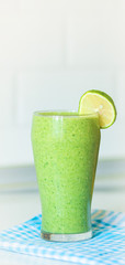 Green smothie in glass with Lemon on top,on blured backgroun, copy space on top