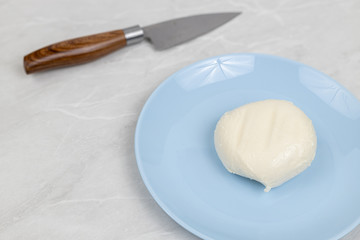 Mozarella cheese served on the blue plate above white marble table