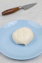 Mozarella cheese served on the blue plate above white marble table