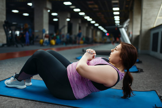 Overweight woman doing exercise on mat in gym