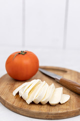 Cheese mozarella with tomato on the wooden cutting board