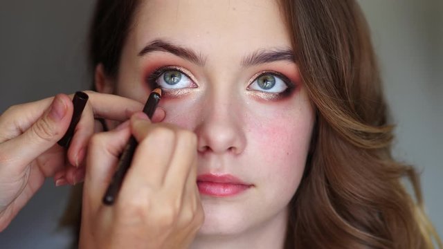 Girl makeup artist paints the eyes of a young girl