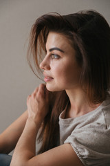 Fototapeta premium portrait of a beautiful young european brunette girl. sit at home on the floor, relax alone, dream, relax, smile. Good morning, comfort at home, calm. Close up portrait