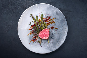 Gegrilltes dry aged Rinderfilet Medaillon Steak natur mit gebratenen Kräuter und Gewürzen als Draufsicht auf einem Modern Design Teller mit Textfreiraum 