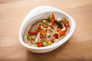Organic plant based hummus with granola dried tomatoes toppings. Perfect for vegan gluten free. Freshly homemade for takeaway and delivery. Healthy food photography.
