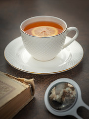 portrait view to cup of hot tea and old book with magnifier glass
