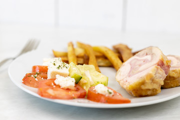 Served rolled chicken with tomato salad with mozarella and french fries