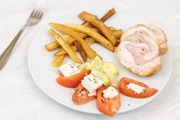 Served rolled chicken with tomato salad with mozarella and french fries