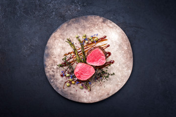 Barbecue dry aged beef fillet medallion steak natural with fried herbs and capers as top view on a modern design plate with copy space
