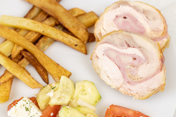 Served rolled chicken with tomato salad with mozarella and french fries