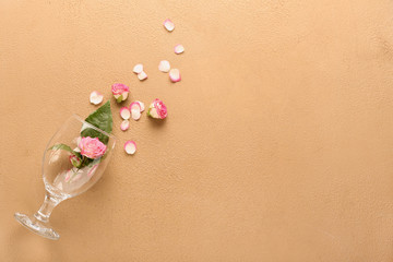 Wineglass and roses on color background
