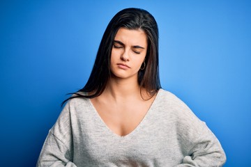 Fototapeta premium Young beautiful brunette woman wearing casual sweater standing over blue background with hand on stomach because indigestion, painful illness feeling unwell. Ache concept.