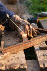 Welding iron. The worker welds the iron parts. Workplace on a pallet with tools.