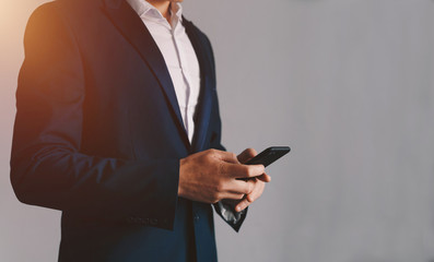 Close-up image of businessman hands using smartphone.
