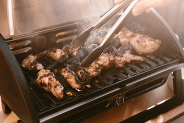 Grill season outdoor in park or balcony. Spring summer grilling. Balcony gas grill. Barbeque fourth of July weekend. Chicken wings on grill. Flame and smoke over grill. BBQ quarantine on balcony.