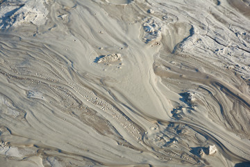 Fototapeta premium Mud flow from a mud volcano. Cracked mud surface. Mudflow texture with cracks.