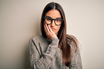 Young beautiful brunette woman wearing casual sweater and glasses over white background thinking looking tired and bored with depression problems with crossed arms.