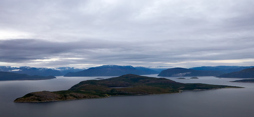 Norway. Summer. In the foreground is a large, elongated island surrounded by water. In the...