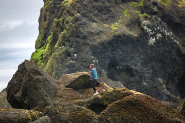 man walking on rocks on the coast, black sand beach in iceland