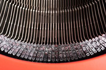 A close-up or a macro shot of the typebars of a retro-style manual typewriter encased in a hinged...