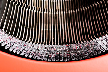 A close-up or a macro shot of the typebars of a retro-style manual typewriter encased in a hinged...