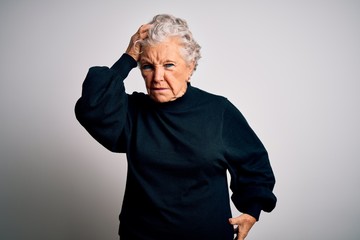 Senior beautiful woman wearing casual black sweater standing over isolated white background confuse and wonder about question. Uncertain with doubt, thinking with hand on head. Pensive concept.