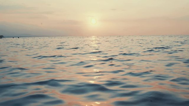 Tropical sunlight is reflecting on water surface. Sunset gives stunning colours to the sky and the ocean. Soft waves. 4K