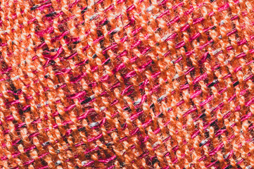 Fabric macro texture. knitted textile. woven background. woolen material. weaving orange and red threads close up
