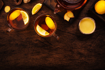 Healing black herbal tea with ginger, honey, lemon. Immune booster drink in glass cup on rustic wooden background with copy space. Top view