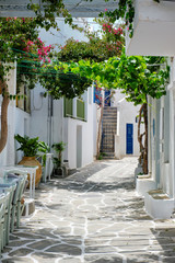Picturesque narrow street with traditional whitewashed houses with cafe tables of Naousa town in famous tourist attraction Paros island, Greece