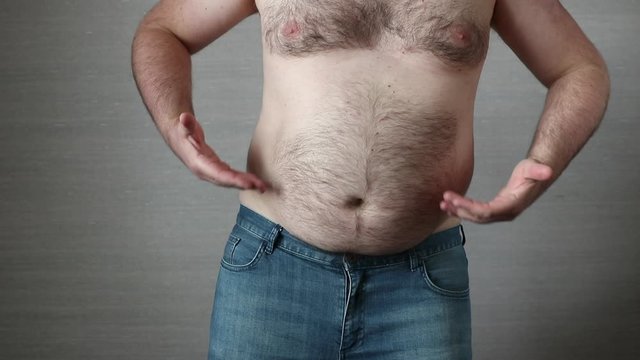 Happy shirtless fat man in jeans dancing and his big obese belly shaking. Overeating problem concept