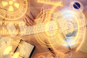 Double exposure of man's hands typing over computer keyboard and tech theme hologram drawing. Top view. Technology concept.