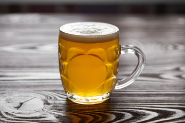 Mug of unfiltered light wheat beer on brown wooden table