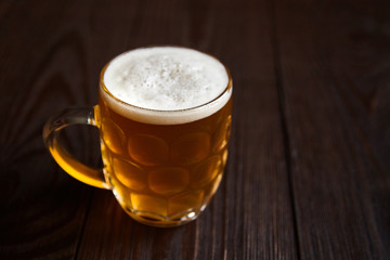 Mug of unfiltered light wheat beer on brown wooden table