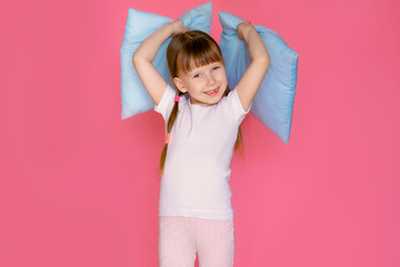 Portrait of a happy cute 5-6 year old baby girl hugging her soft pillow, enjoy the weekend, feel...