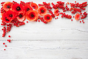 Summer white wooden background with red poppies and with red currant berries for congratulations, text.
