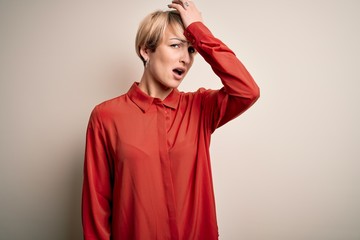 Young beautiful business blonde woman with short hair standing over isolated background surprised...